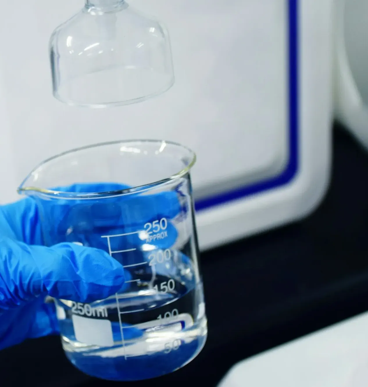 Gloved hand holding a laboratory beaker of water