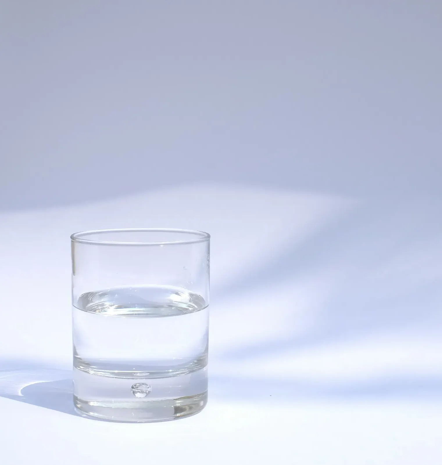 Single glass of clear water on a pale table