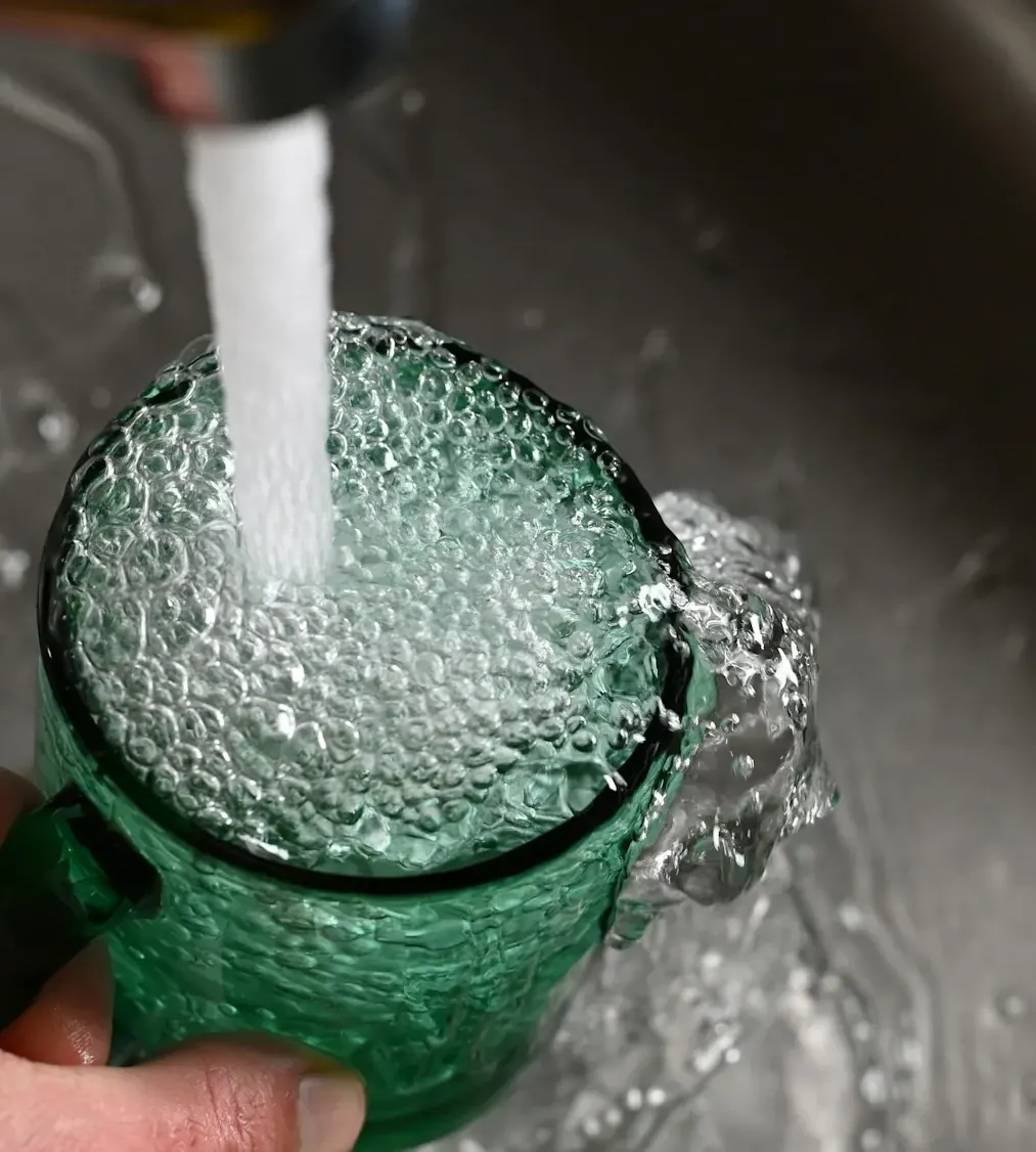 Water pouring into a glass held under a kitchen faucet