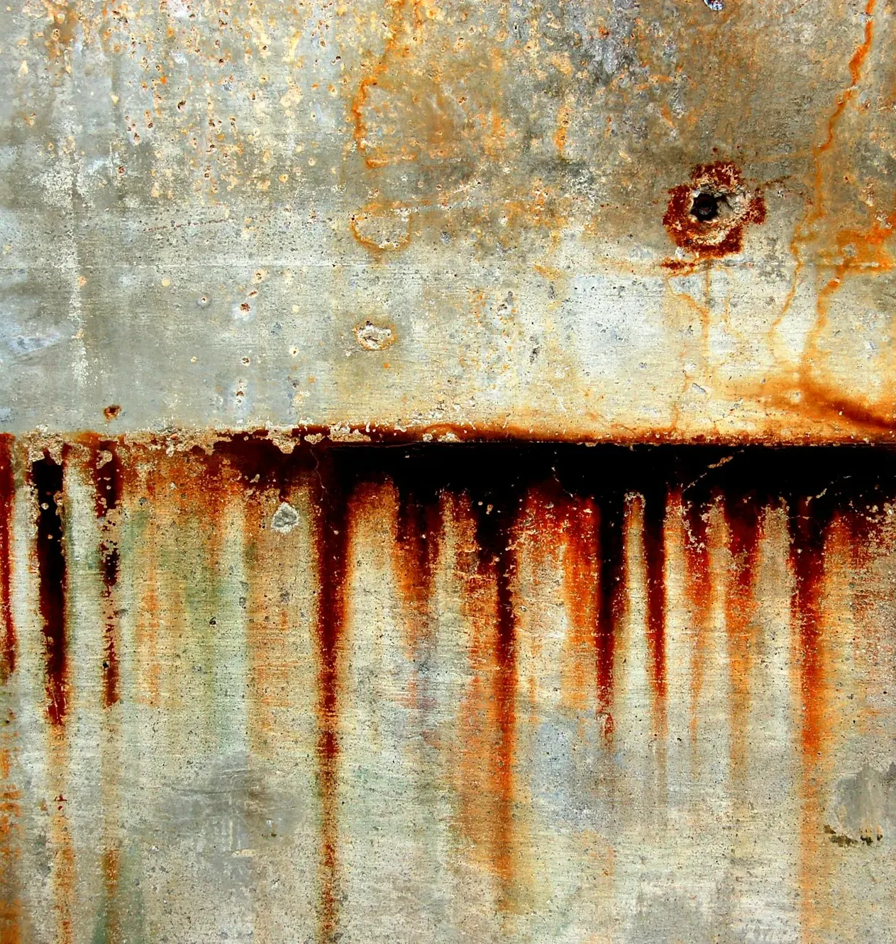 Rust streaks running down a weathered concrete wall