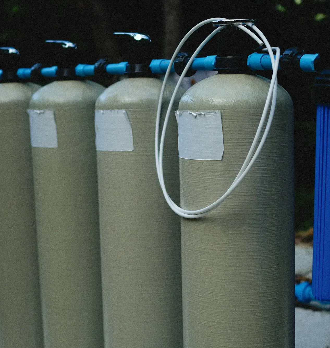 Row of tall water treatment tanks on blue piping