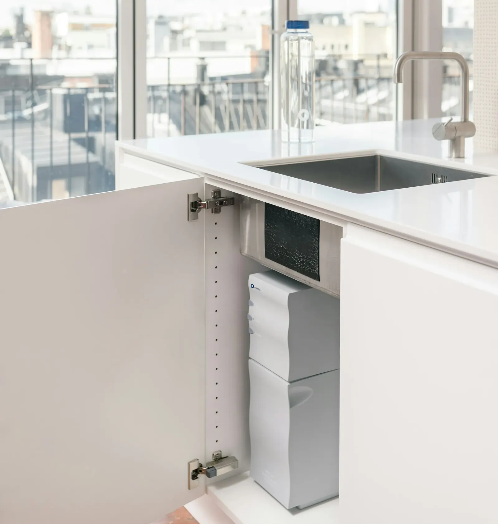 Open kitchen cabinet showing a compact under-sink filter