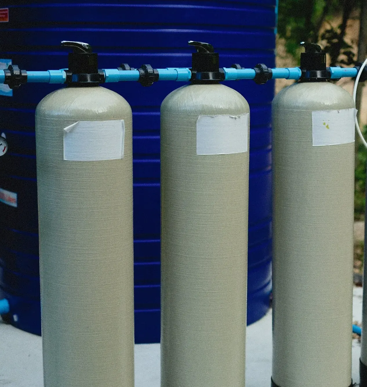 Tall water softener tanks connected with blue piping