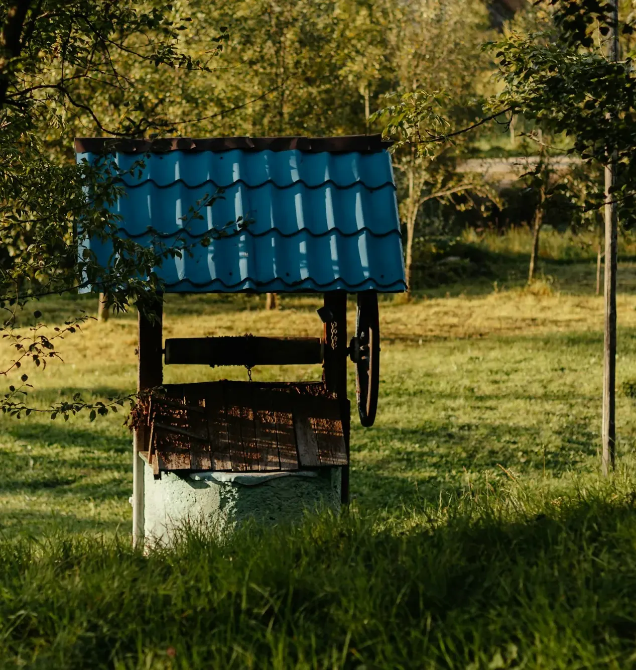Old wooden-roofed well in a green orchard
